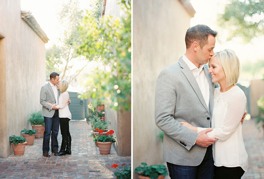 Groom gently kisses and holds bride near house setting 