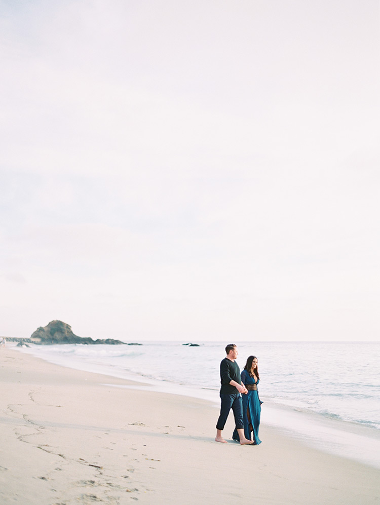 holding hands on the pale sand of Victoria Beach