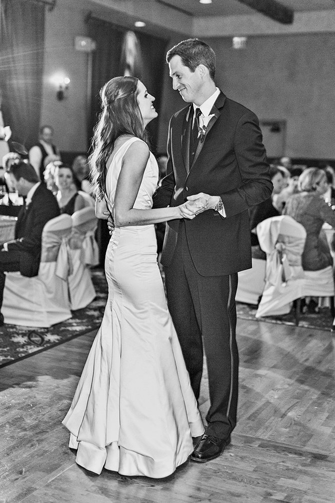 Black & white photo of a bride & groom smiling at one another during their first dance. Reception