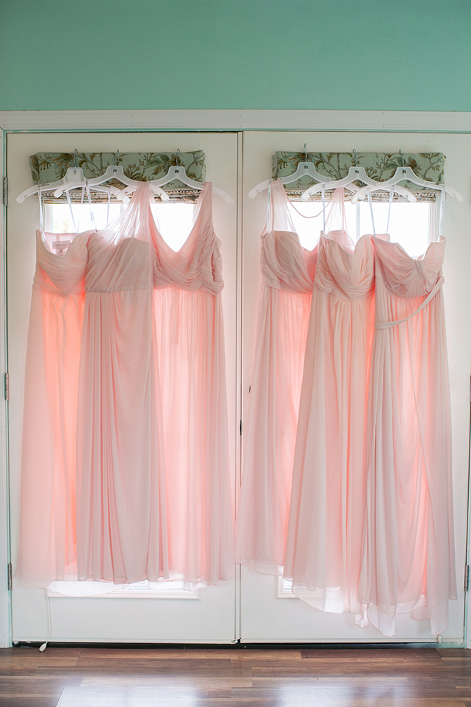 Light pink bridesmaids dresses hanging on door. Wedding photography inspiration and ideas.