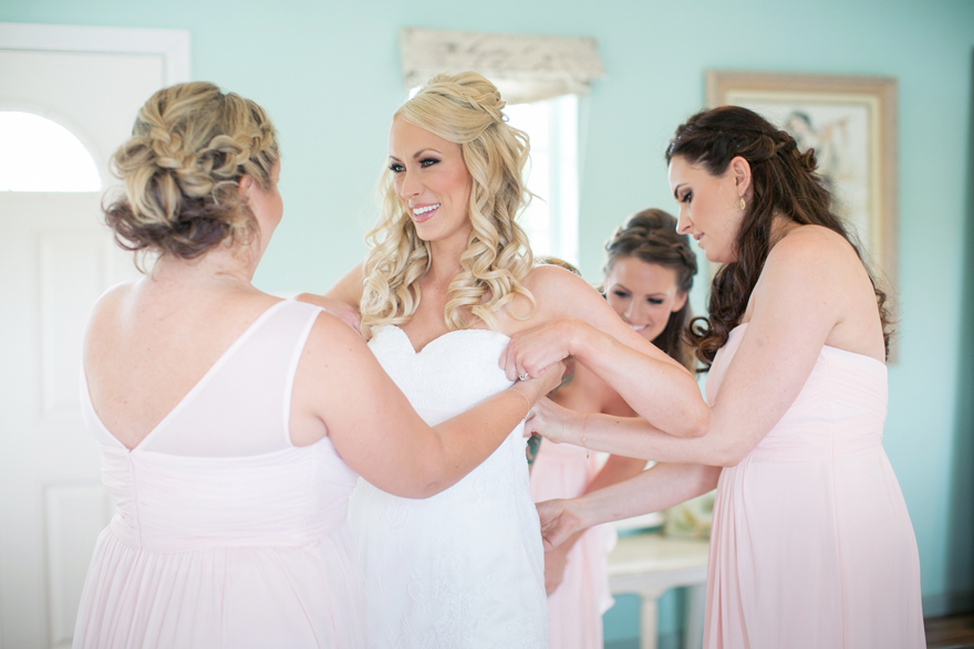 Bridesmaids helping beautiful blonde bride into her strapless wedding dress. Wedding inspiration.