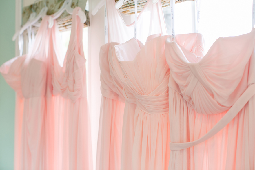 Light pink bridesmaids dresses hanging on door. Wedding photography inspiration and ideas.