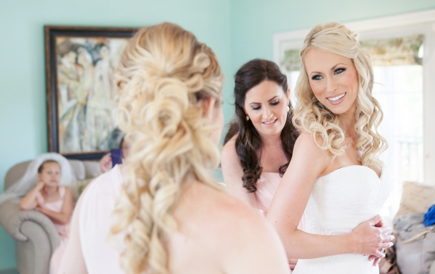 Bridesmaids helping beautiful blonde bride into her strapless wedding dress. Wedding inspiration.