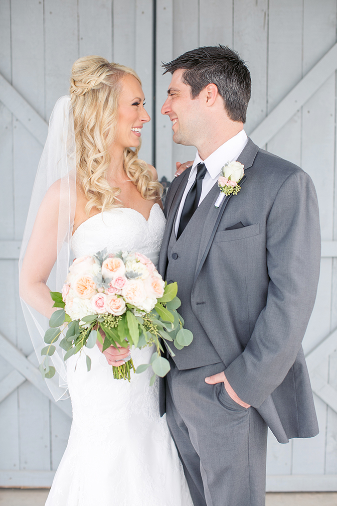 Blonde bride and groom smile at each other on their wedding day. Strapless a-line dress & grey suit.
