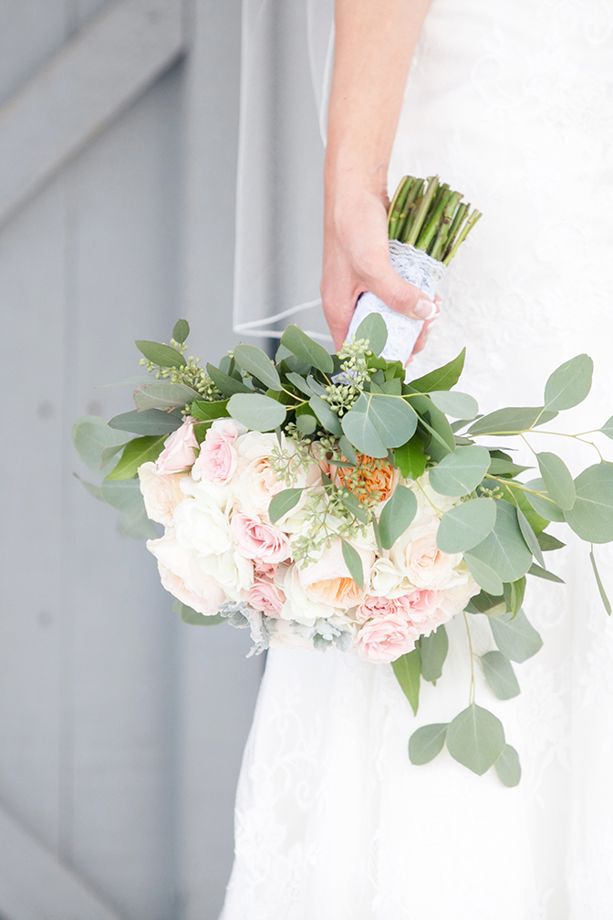 Bride holds beautiful white and light pink rose bouquet with french manicure on her wedding day.