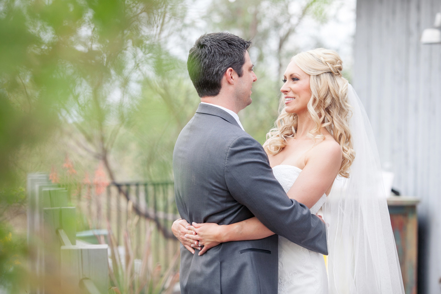 Blonde bride and groom hugging and smiling at each other romantically on their wedding day.