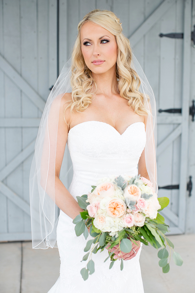 Gorgeous blonde bride in strapless a-line lace wedding dress with pink rose bouquet.